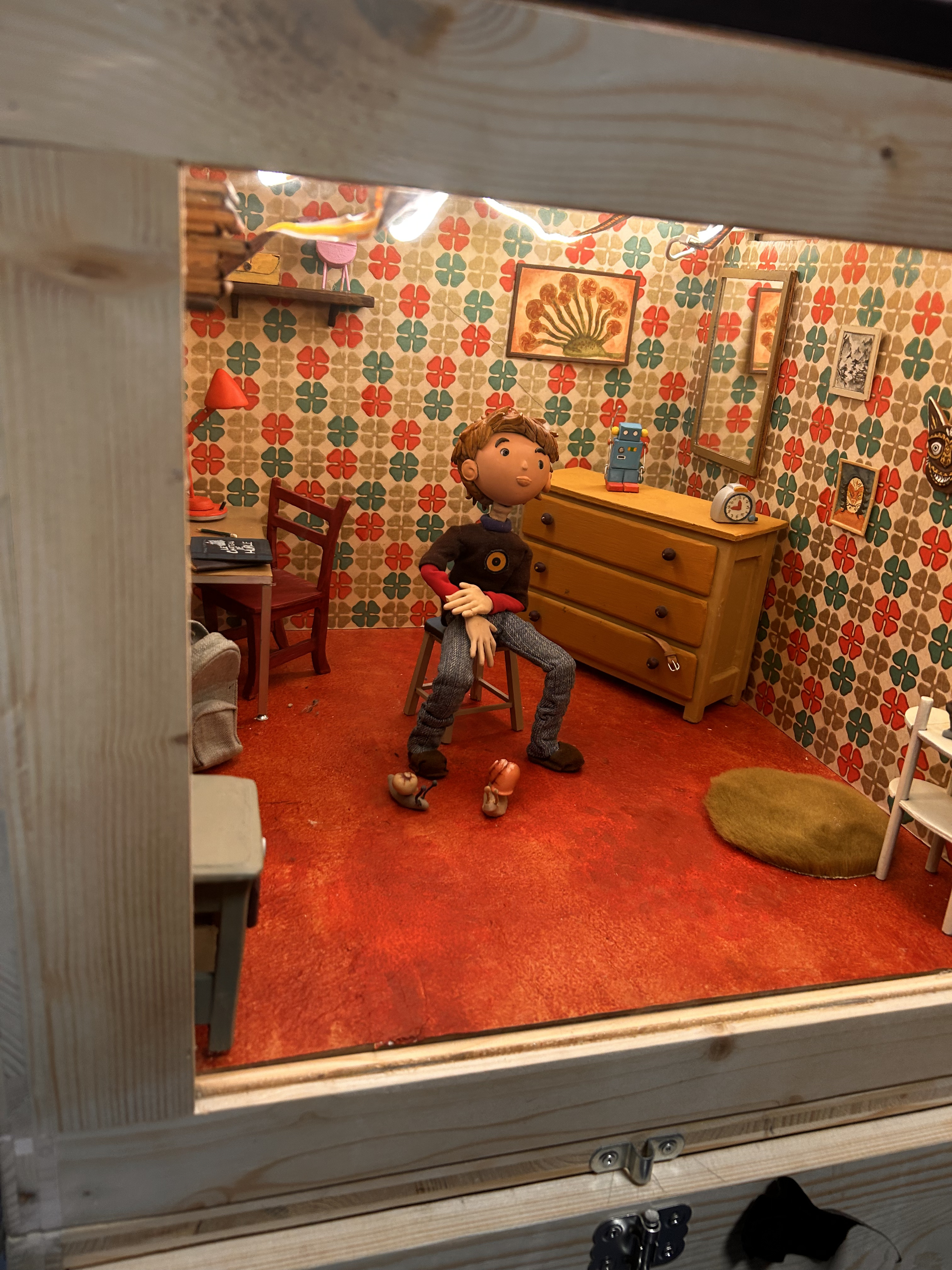 Une marionnette assise sur une chaise dans un décor miniature
