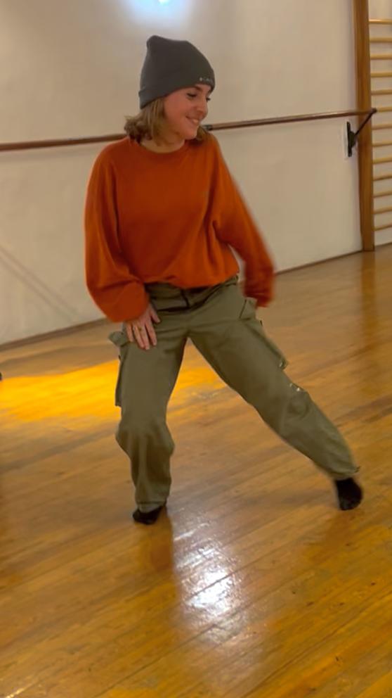Une danseuses tend la jambe sur un parquet 