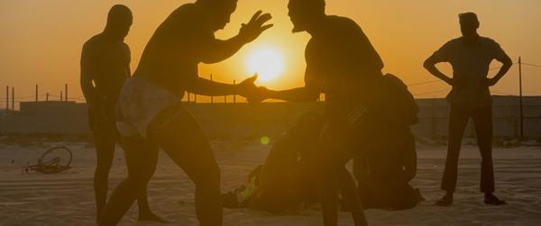 Deux lutteurs s'affrontent devant le coucher de soleil sur le sable chaud.