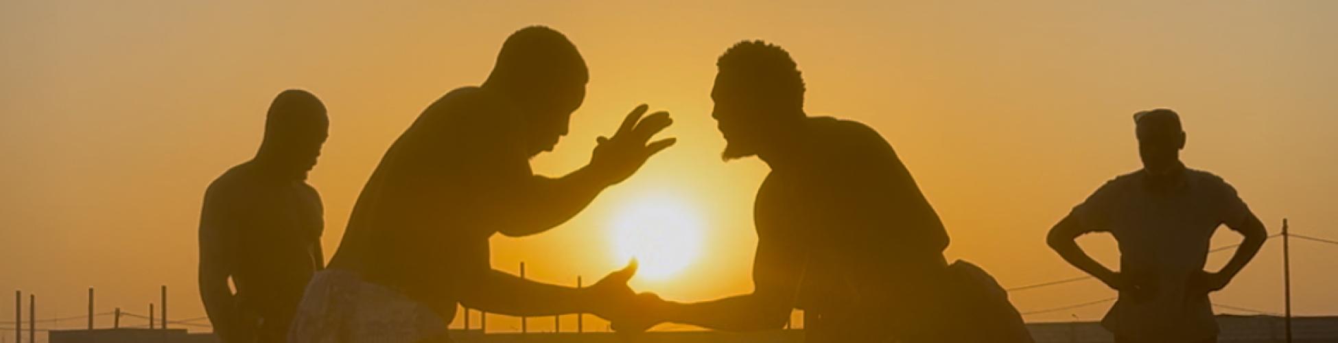 Deux lutteurs s'affrontent devant le coucher de soleil sur le sable chaud.